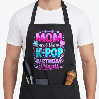 Princess korean apron - Stacked pink and blue text reading MOM of the K-POP BIRTHDAY Princess with headphones, wand — shown on a black cotton canvas apron against a white background