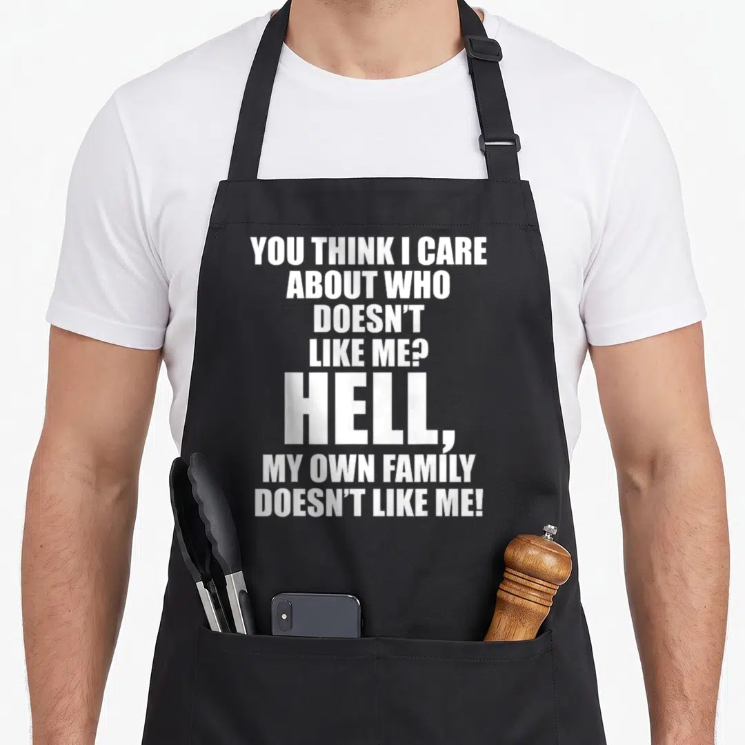 Care family aprons - White stacked text reading You Think I Care About Who Doesn't Like Me Hell My Own Family Doesn't — shown on a black cotton canvas apron against a white background