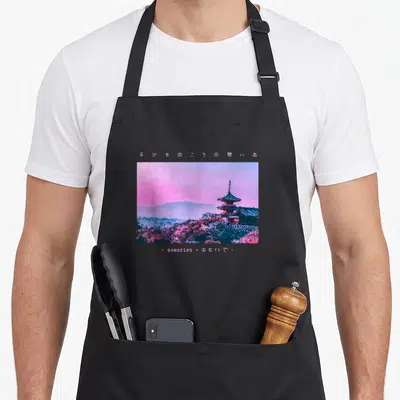 Cute japanese streetwear apron - Pixel art pagoda landscape in pink and blue with Japanese text and word memories below — shown on a black cotton canvas apron against a white background