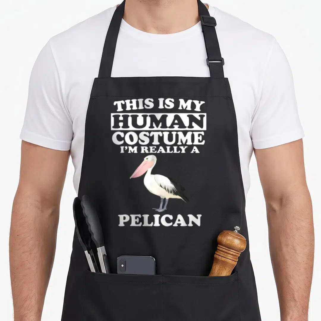 Human pelican apron - Pelican with pink bill and text This Is My Human Costume I'm Really A Pelican — shown on a black cotton canvas apron against a white background