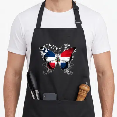 Dominican butterfly apron - Butterfly with red white blue flag wings surrounded by white swirls and flowers — shown on a black cotton canvas apron against a white background