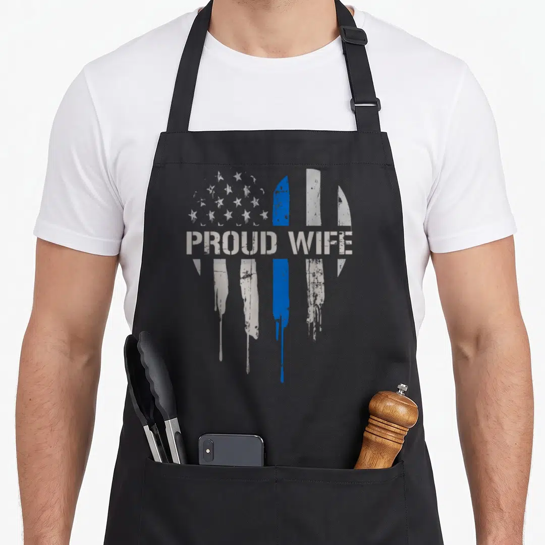 Thin wife apron - PROUD WIFE text over distressed flag with blue stripe — shown on a black cotton canvas apron against a white background