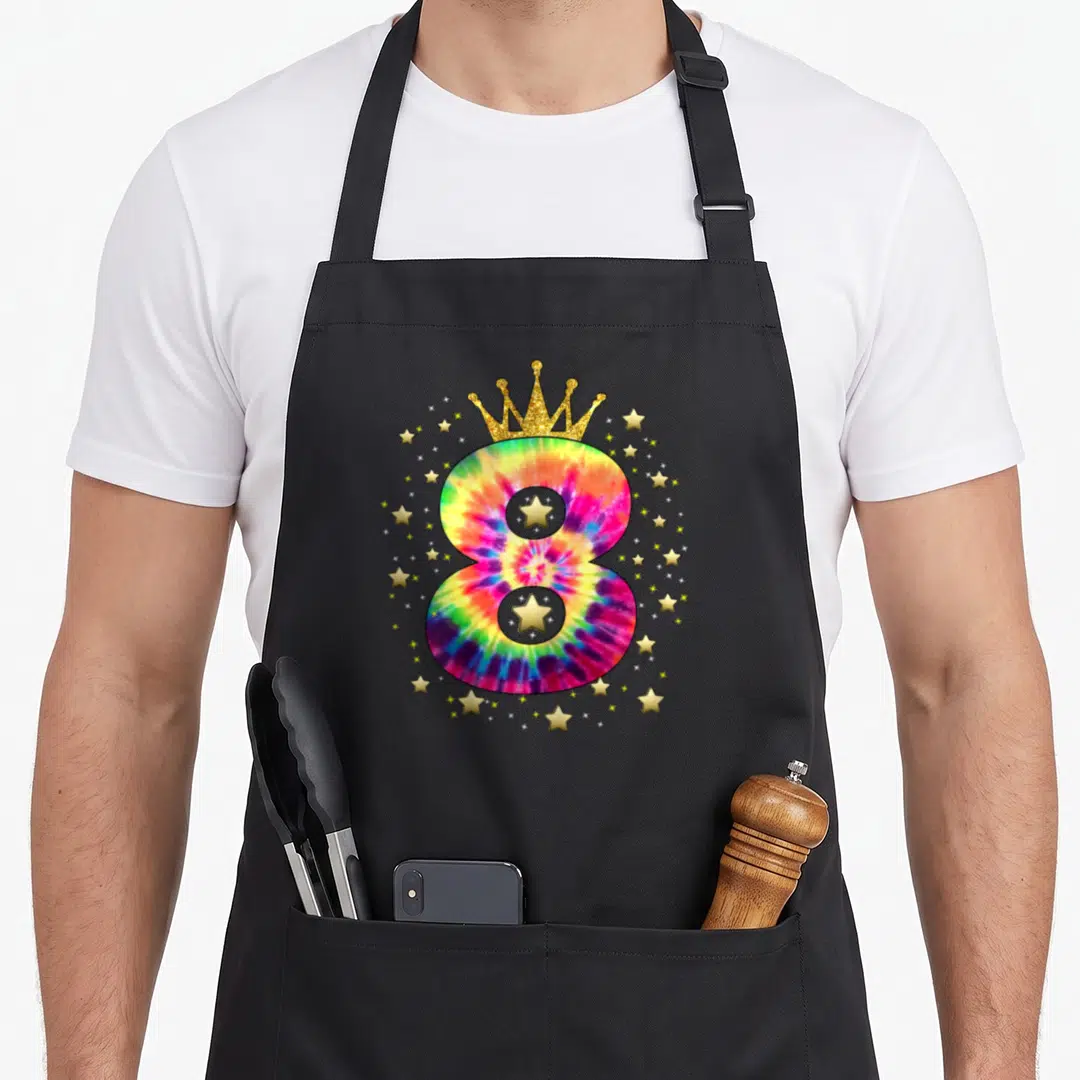 Colorful tie apron - Tie-dye number 8 with gold crown and scattered gold stars on black fabric — shown on a black cotton canvas apron against a white background