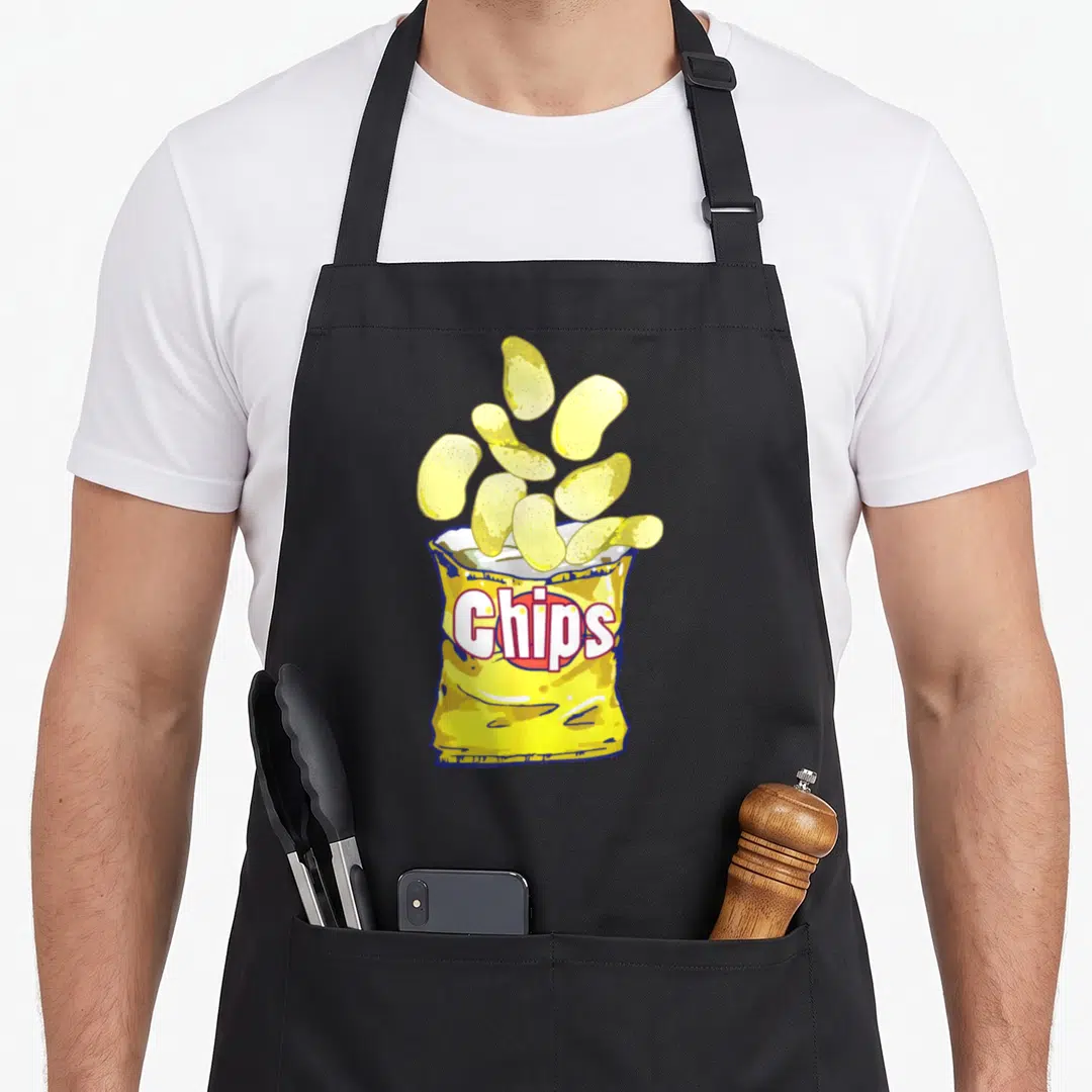 Game potato apron - Cartoon yellow bag of chips with floating crisps and red outlined text — shown on a black cotton canvas apron against a white background