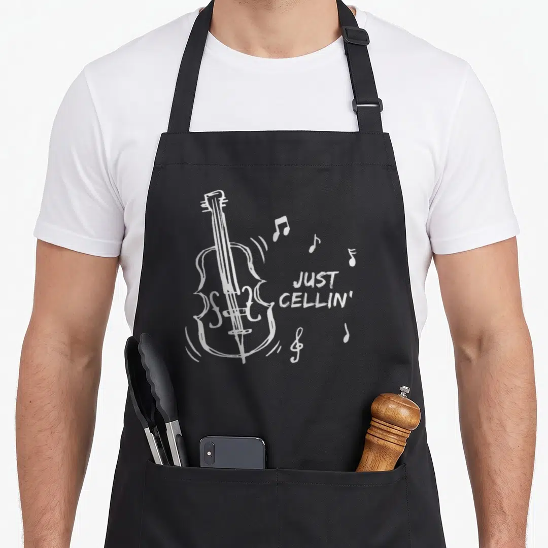 Cellin musician cello apron - White line-art cello with musical notes and Just Cellin text — shown on a black cotton canvas apron against a white background