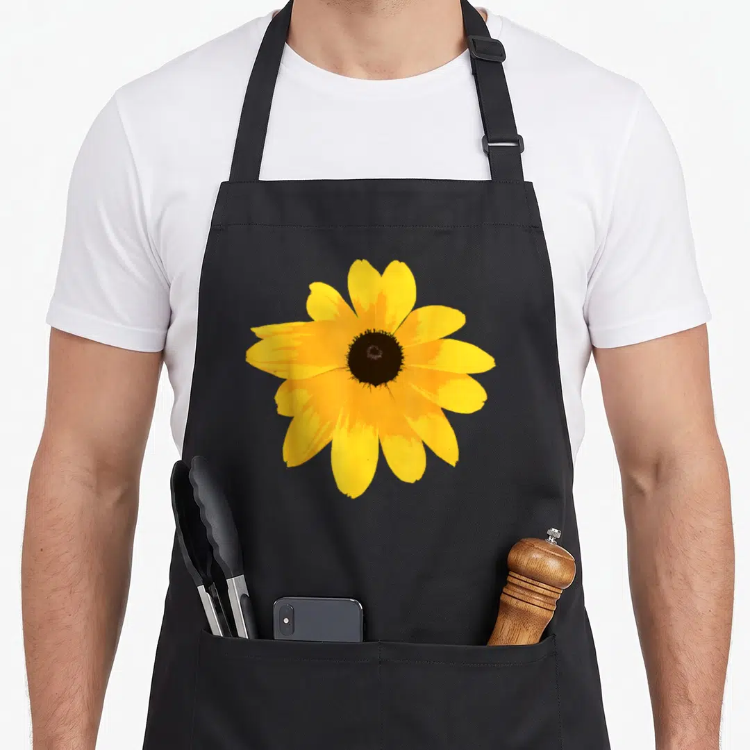 Susan eyed apron - Single yellow flower with brown center photo print — shown on a black cotton canvas apron against a white background