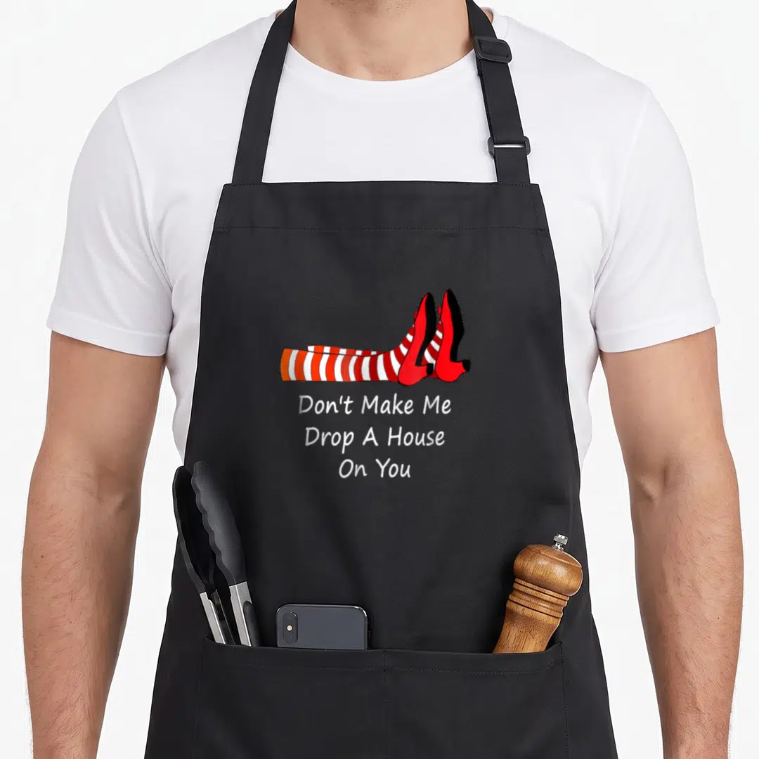 Wizard novelty apron - Cartoon legs in red and white striped stockings with red heels above three lines of white text — shown on a black cotton canvas apron against a white background