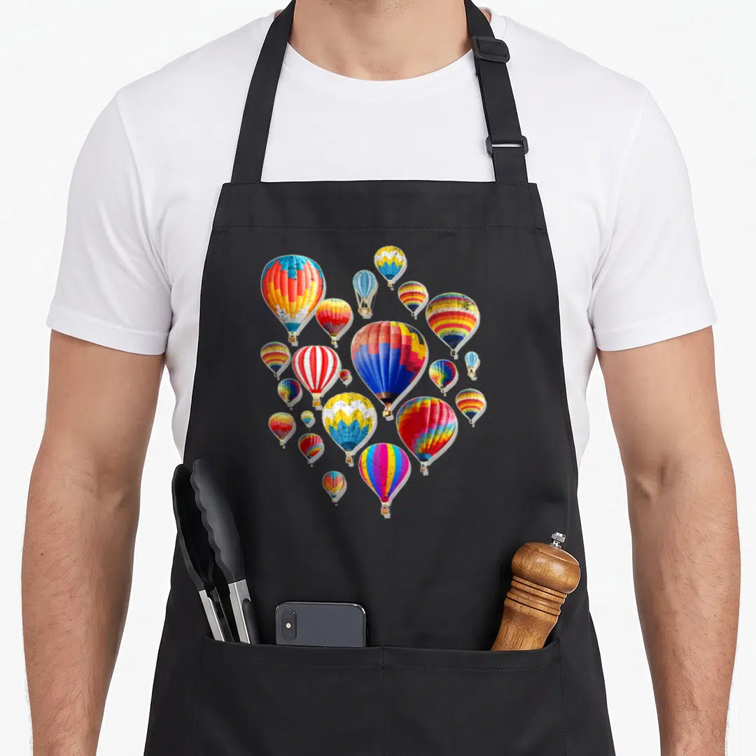 Air balloon apron - Cluster of multicolored hot air balloons in red, blue, yellow, and green — shown on a black cotton canvas apron against a white background