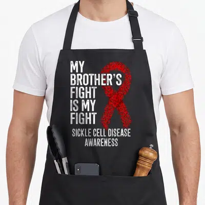 Brother sickle cell awareness apron - Red stippled ribbon and white distressed text reading MY BROTHERS FIGHT IS MY — shown on a black cotton canvas apron against a white background