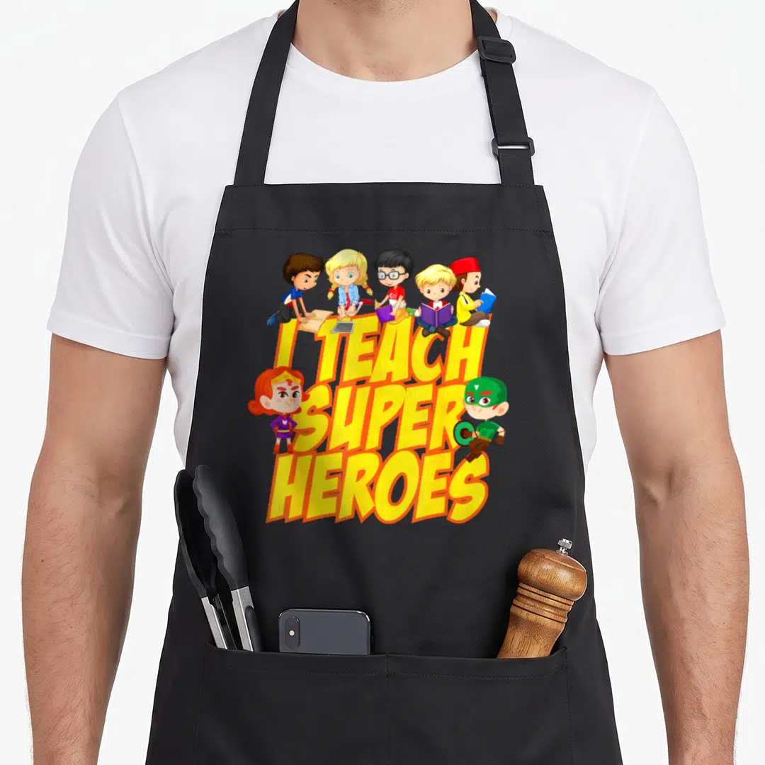 Heroe teaching teacher apron - Yellow text I Teach Super Heroes with five students sitting on letters and two cartoon — shown on a black cotton canvas apron against a white background