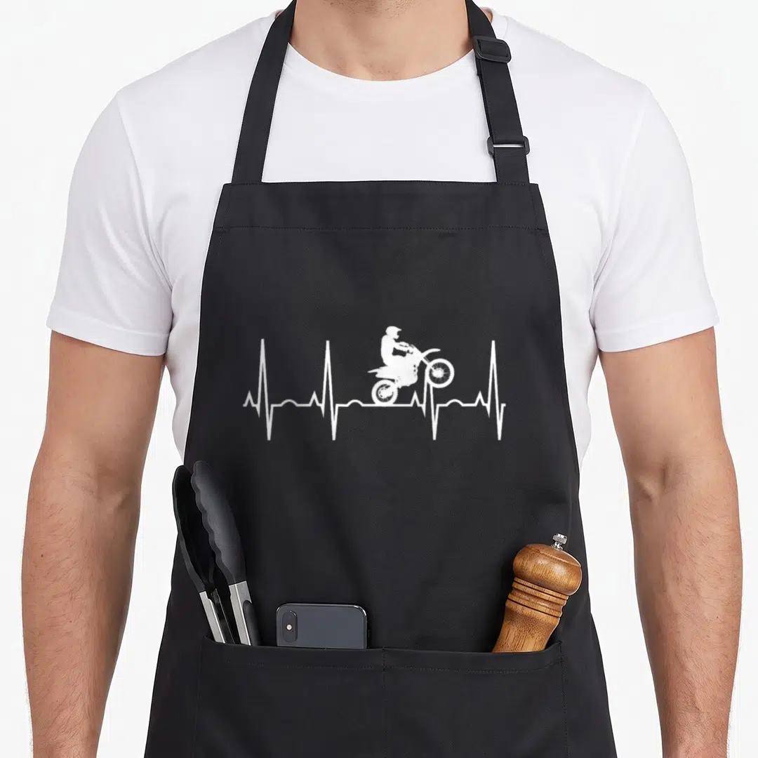 Heartbeat bike apron - White motocross rider jumping over a white EKG heartbeat line in minimalist style — shown on a black cotton canvas apron against a white background