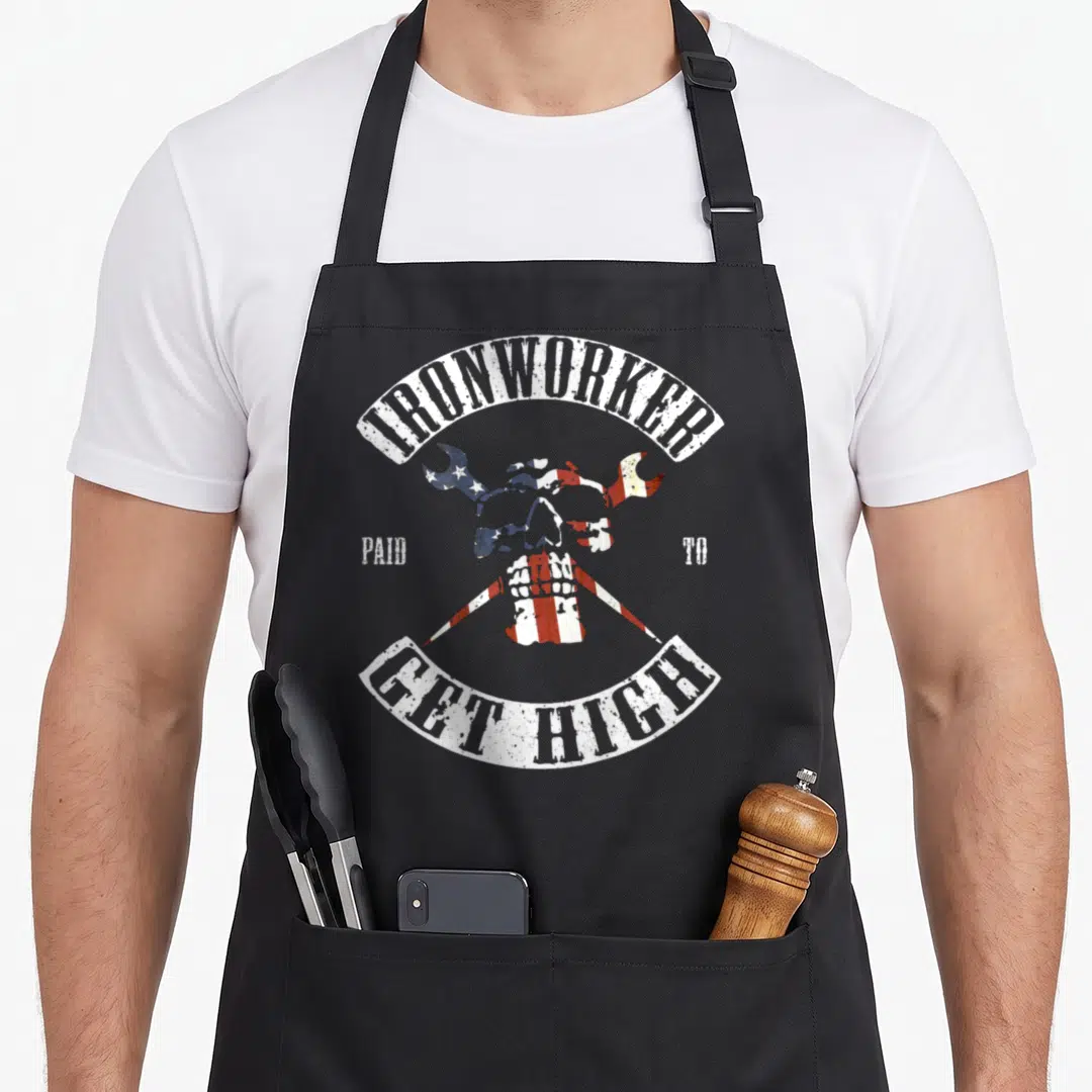 Paid ironworker apron - Distressed skull with crossed wrenches and ironworker text in red white blue — shown on a black cotton canvas apron against a white background