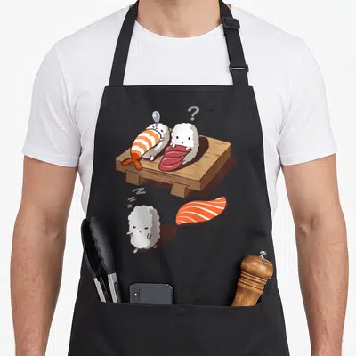 Japanese sushi apron - Cartoon nigiri sushi on wooden board with salmon and sleeping rice ball with zzz symbols — shown on a black cotton canvas apron against a white background