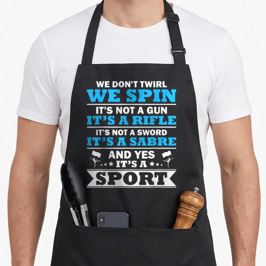 Guard band humor apron - Stacked white and blue text reading We Don Twirl We Spin flanked by two flag bearing majorette — shown on a black cotton canvas apron against a white background