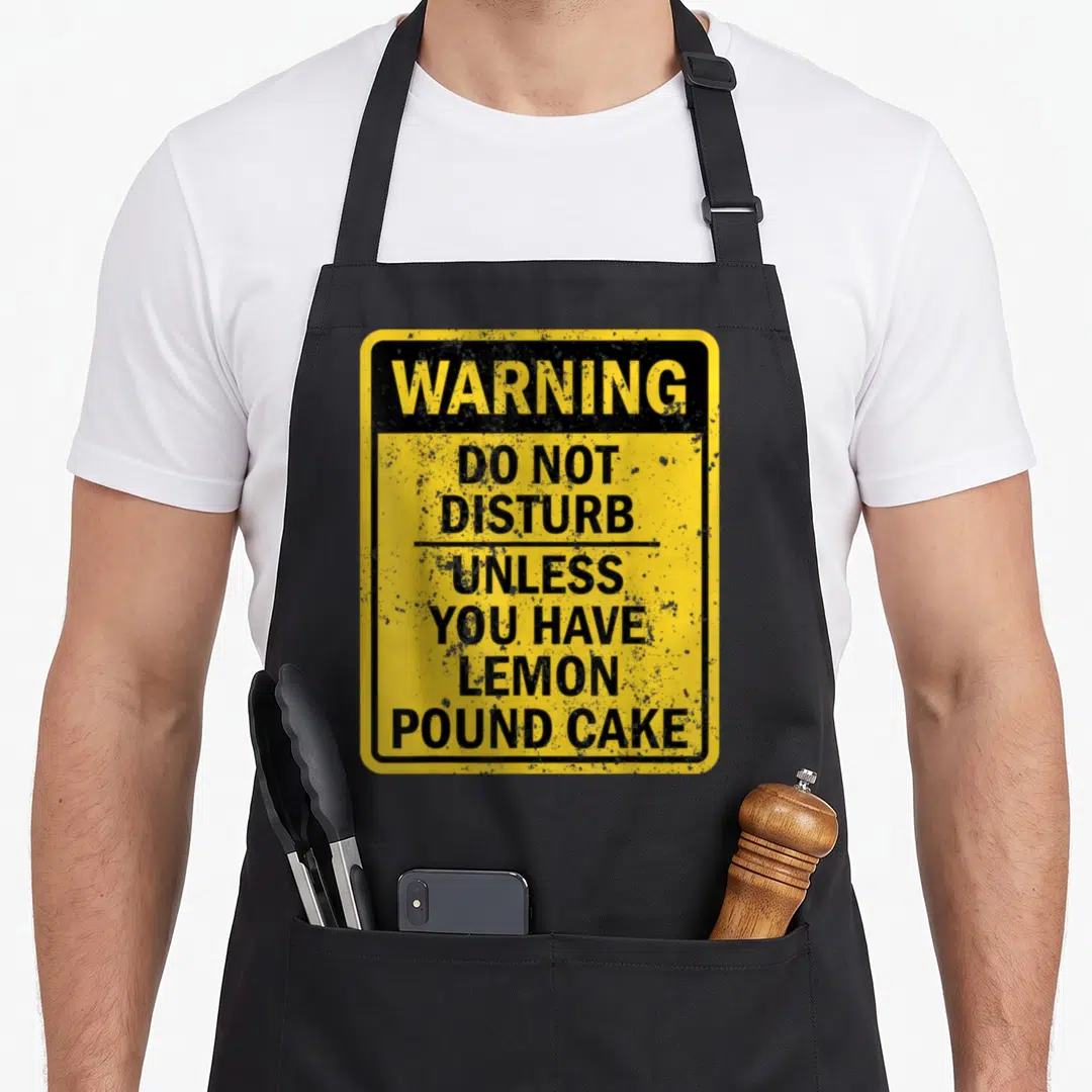 Cake lemon aprons - Yellow and black warning sign reading do not disturb unless you have lemon pound cake — shown on a black cotton canvas apron against a white background