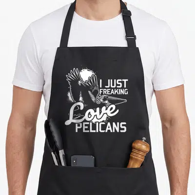 Pelican freaking love apron - White cartoon pelican with sun and text I Just Freaking Love Pelicans — shown on a black cotton canvas apron against a white background