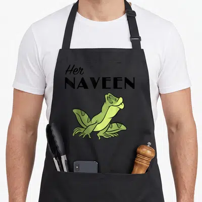 Naveen princess apron - Stacked black text Her NAVEEN above a sitting green cartoon frog — shown on a black cotton canvas apron against a white background