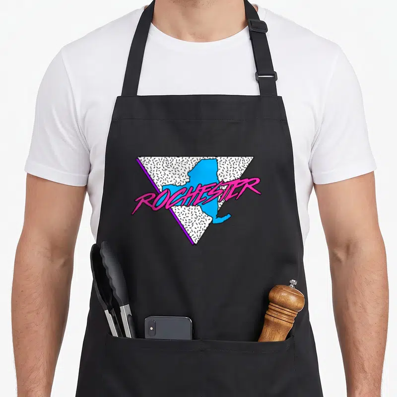 Neon new york apron - Pink ROCHESTER text over blue NY map in white and black inverted triangle — shown on a black cotton canvas apron against a white background