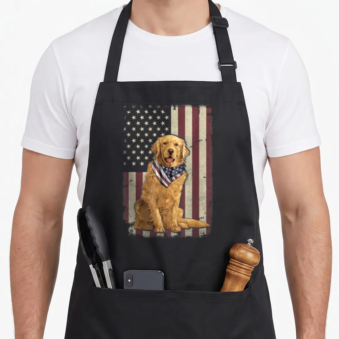 Flag golden retriever apron - Realistic golden retriever sitting with flag bandana in front of distressed stars — shown on a black cotton canvas apron against a white background
