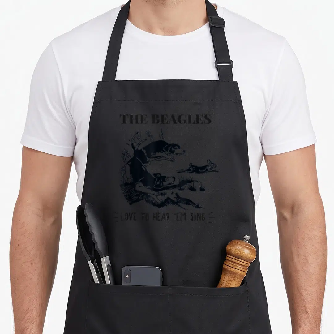 Rabbit beagle apron - Two black beagles chasing a rabbit with text THE BEAGLES LOVE TO HEAR 'EM SING — shown on a black cotton canvas apron against a white background