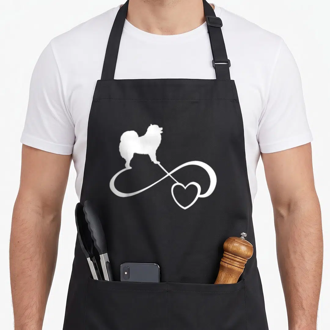 Samoyed dog breed aprons - White dog silhouette on infinity heart symbol — shown on a black cotton canvas apron against a white background