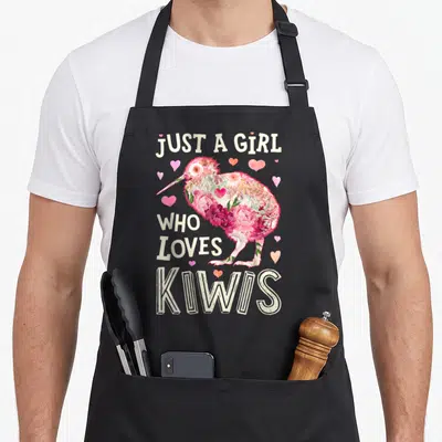 Kiwi the floral apron - Stacked text Just a Girl Who Loves Kiwis around a floral bird silhouette with hearts — shown on a black cotton canvas apron against a white background