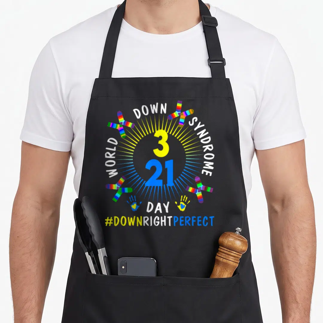 Right chromosomes apron - 3 21 number with rainbow chromosomes and #DOWNRIGHTPERFECT text — shown on a black cotton canvas apron against a white background
