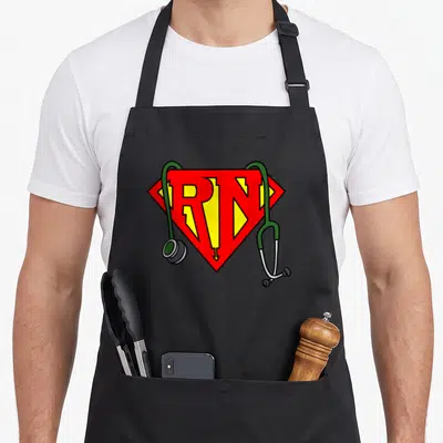Funny superhero nurse apron - Red and yellow RN shield with green stethoscope cartoon graphic — shown on a black cotton canvas apron against a white background
