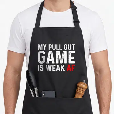 Pull game aprons - White stacked text reading MY PULL OUT GAME IS WEAK AF with red AF highlight — shown on a black cotton canvas apron against a white background