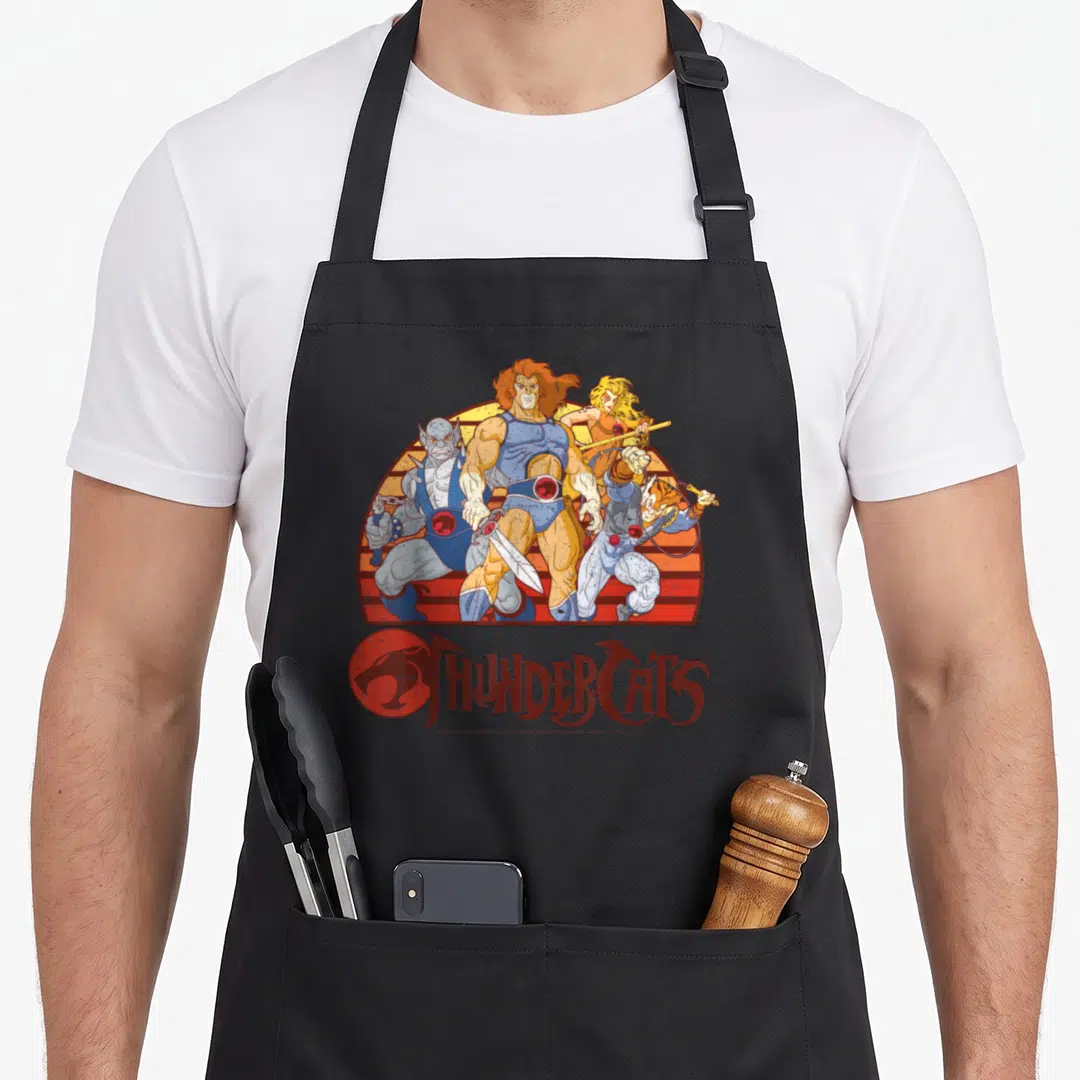 Sunset thunderstorm apron - Four ThunderCats characters grouped before red and orange striped semi-circle sun with logo — shown on a black cotton canvas apron against a white background