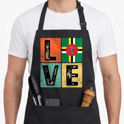 Dominica pride apron - Distressed LOVE text in colored squares with Dominican flag and parrot inside the O — shown on a black cotton canvas apron against a white background