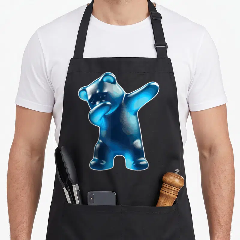 Blue bear apron - Glossy blue gummy bear doing a dab pose with white outline — shown on a black cotton canvas apron against a white background