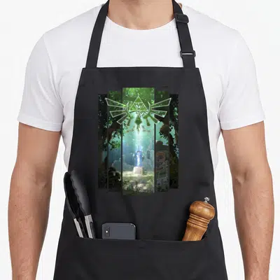 Master wood apron - Five panel Triforce symbol over sword in stone forest scene with cartoon character detail in green — shown on a black cotton canvas apron against a white background