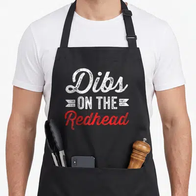 Ginger st patrick day aprons - Stacked Dibs ON THE Redhead text in white and red script with banners — shown on a black cotton canvas apron against a white background