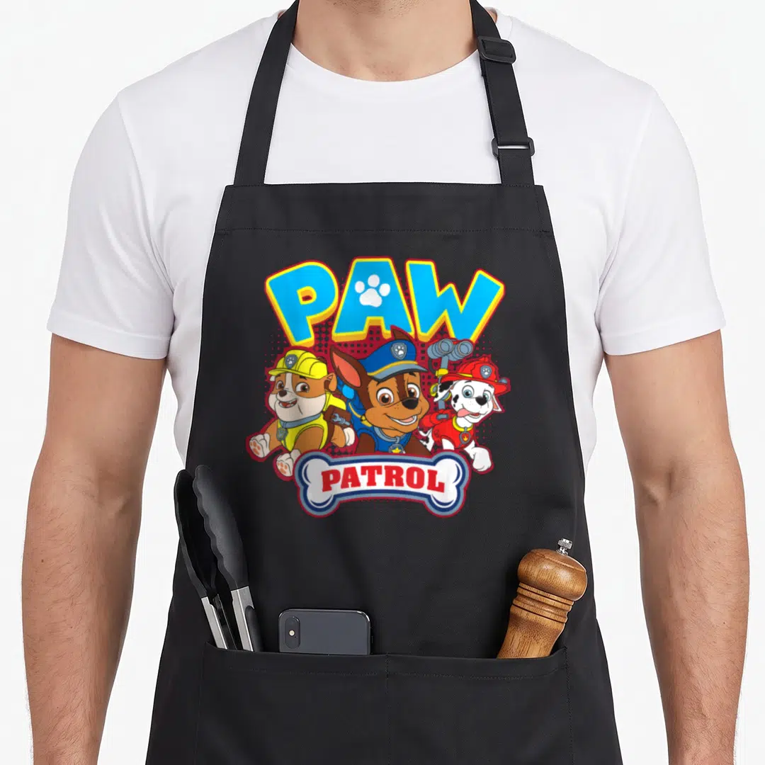Rubble marshalls apron - Stacked PAW PATROL text above three running cartoon pups in rescue uniforms — shown on a black cotton canvas apron against a white background