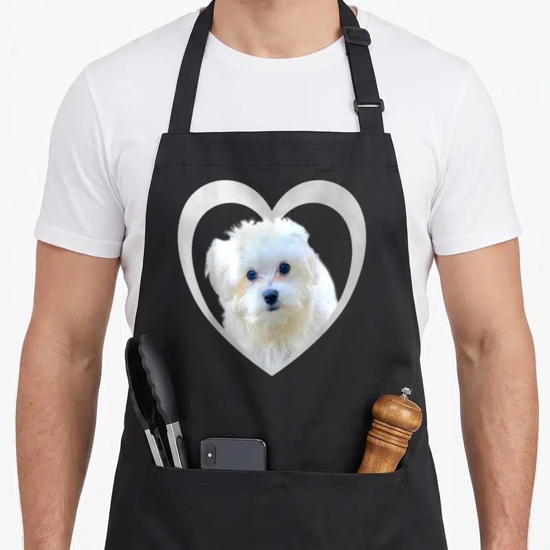 Cute maltese dog apron - Photo of white dog face inside white heart outline — shown on a black cotton canvas apron against a white background