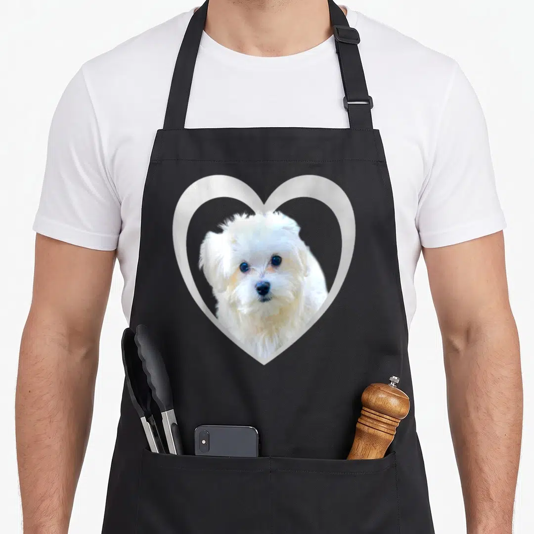 Cute maltese dog apron - Photo of white dog face inside white heart outline — shown on a black cotton canvas apron against a white background
