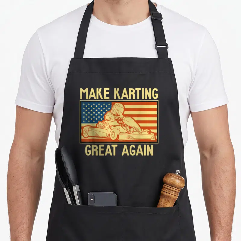 Funny kart karting apron - Retro go-kart driver illustration with flag background and text — shown on a black cotton canvas apron against a white background