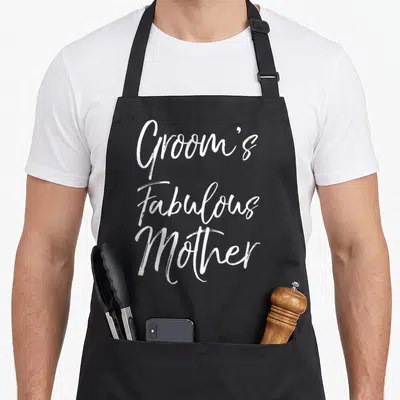 Family groom bridal apron - White script text reading Groom's Fabulous Mother stacked in three lines — shown on a black cotton canvas apron against a white background