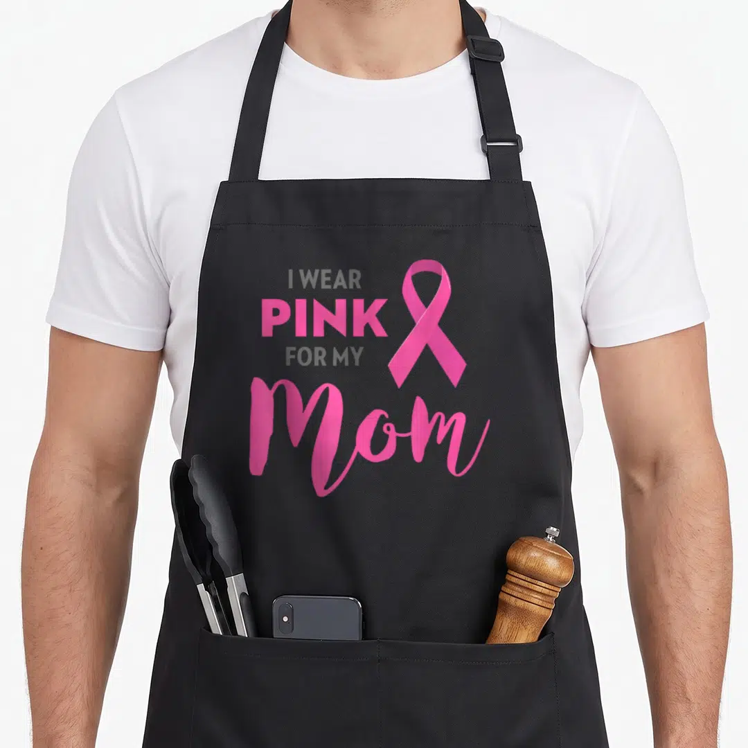 Funny breast cancer awareness aprons - I WEAR PINK FOR MY Mom text with pink ribbon on grey background — shown on a black cotton canvas apron against a white background