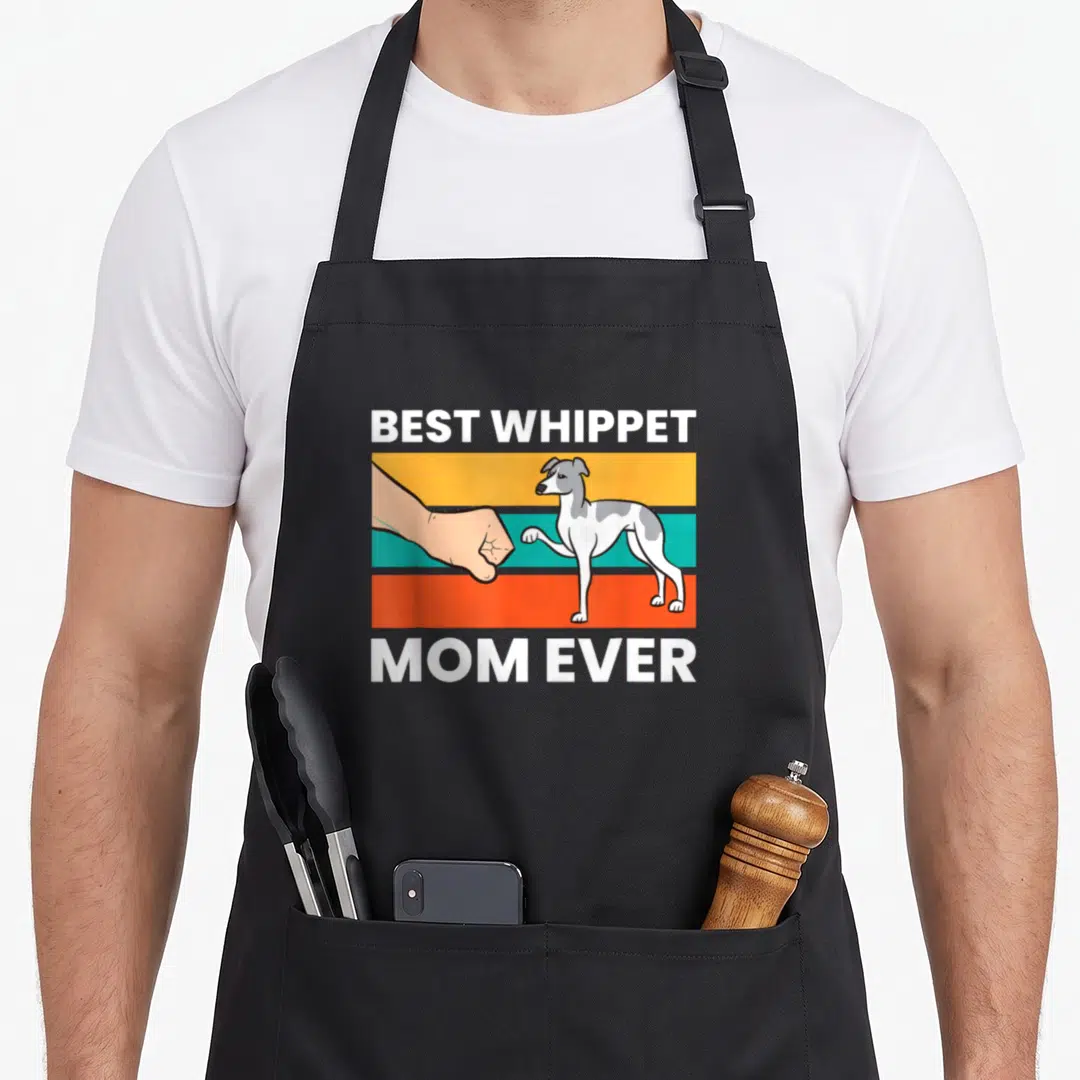 Cute whippet apron - Cartoon whippet and human fist bumping over orange teal and yellow stripes with text BEST WHIPPET — shown on a black cotton canvas apron against a white background