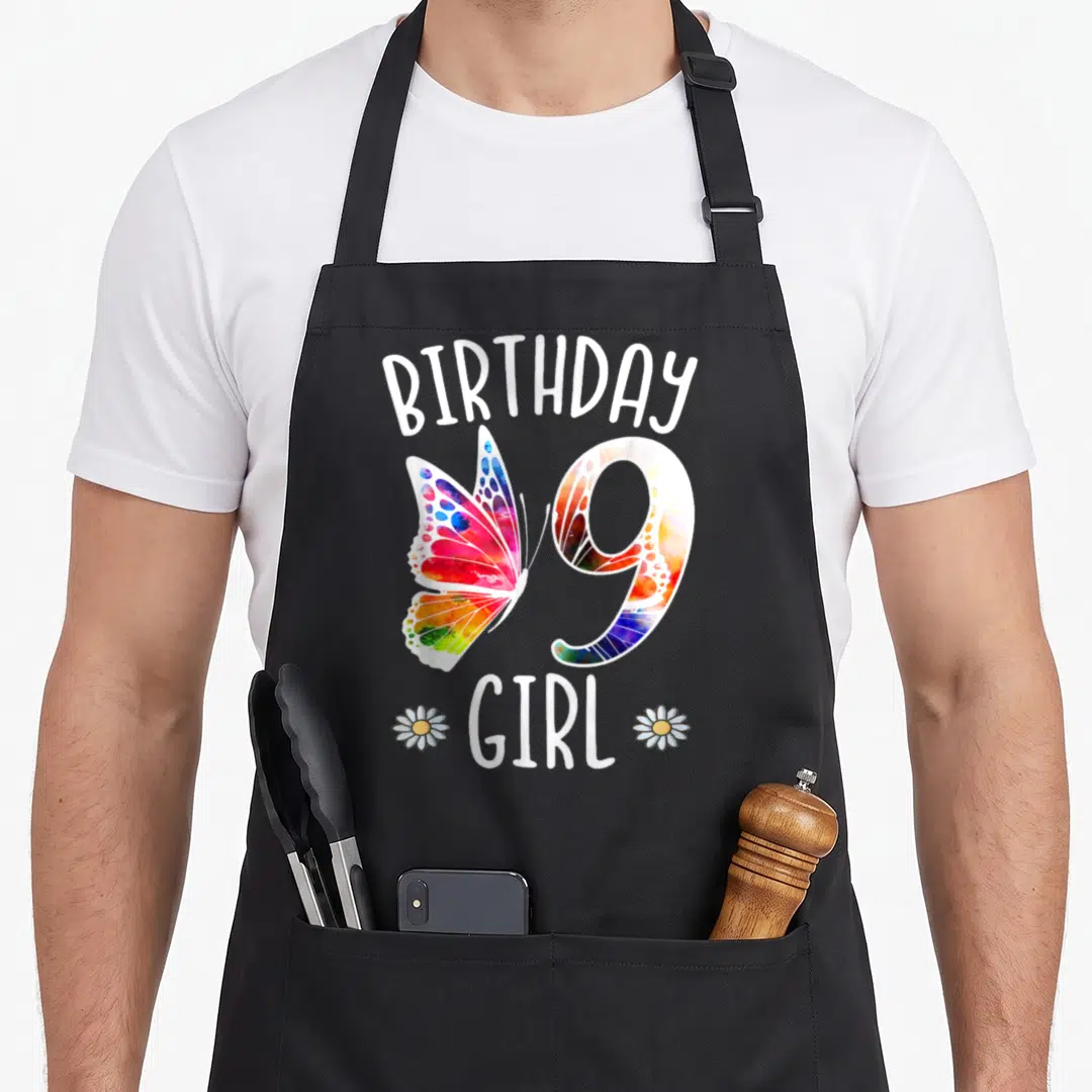Funny 9th butterfly aprons - Watercolor butterfly overlaps number 9 with BIRTHDAY GIRL text and two daisies — shown on a black cotton canvas apron against a white background