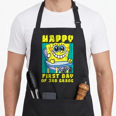 3rd school apron - SpongeBob sitting in a chair with yellow text reading Happy First Day of 3rd Grade — shown on a black cotton canvas apron against a white background