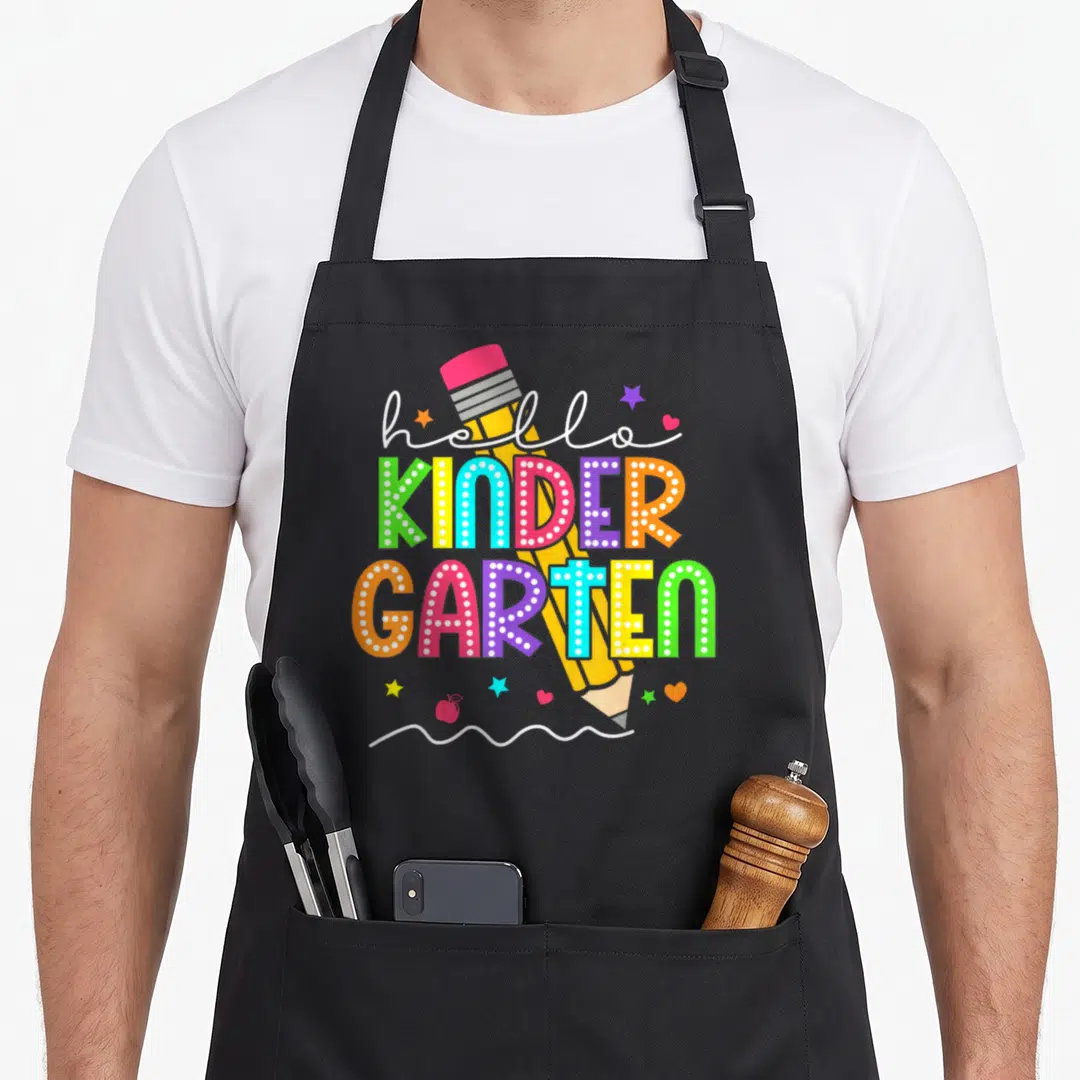Kinder school kindergarten teacher apron - Hello KINDER GARTEN text behind yellow pencil with colorful stars and hearts — shown on a black cotton canvas apron against a white background