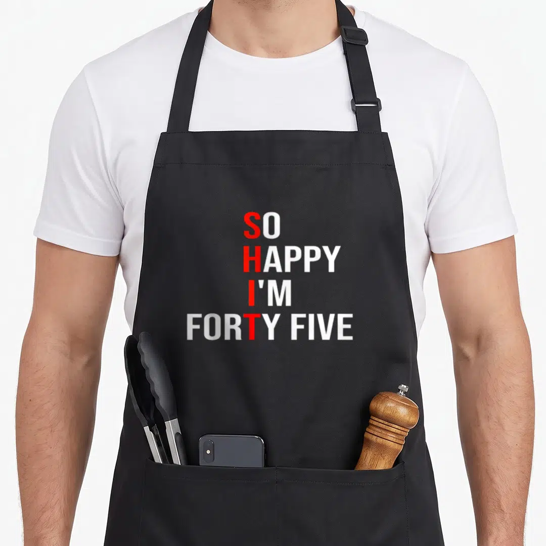 Forty five birthday apron - Red and white stacked text reading So Happy I'm Forty Five on black background — shown on a black cotton canvas apron against a white background