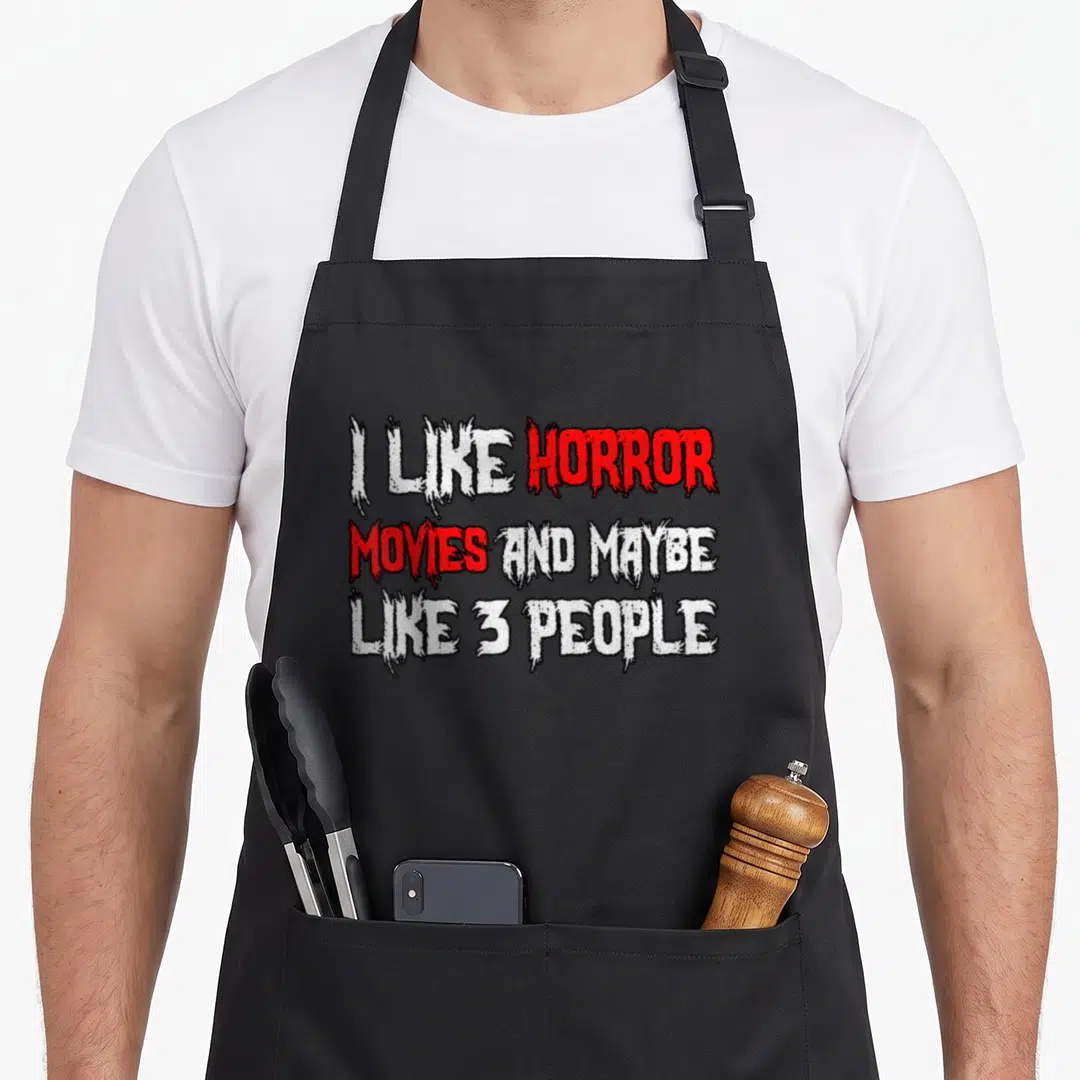 Movy horror apron - Distressed white and red text reading I like horror movies and maybe 3 people — shown on a black cotton canvas apron against a white background
