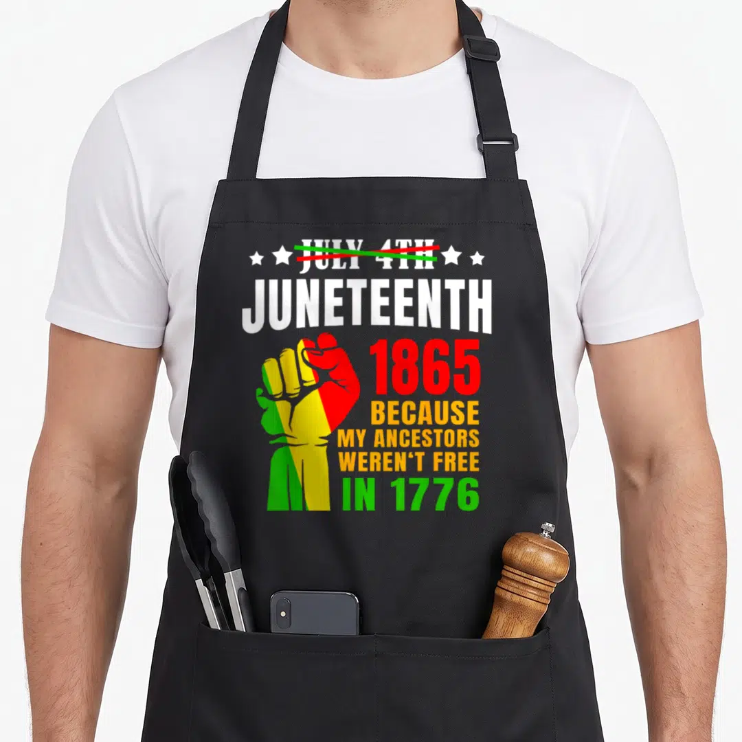 June african american aprons - Raised fist in red yellow and green with text about ancestors not being free in 1776 — shown on a black cotton canvas apron against a white background