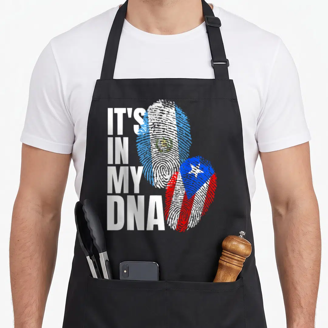 Puerto guatemalan aprons - It's In My DNA text next to two fingerprints filled with flag patterns in white blue and red — shown on a black cotton canvas apron against a white background