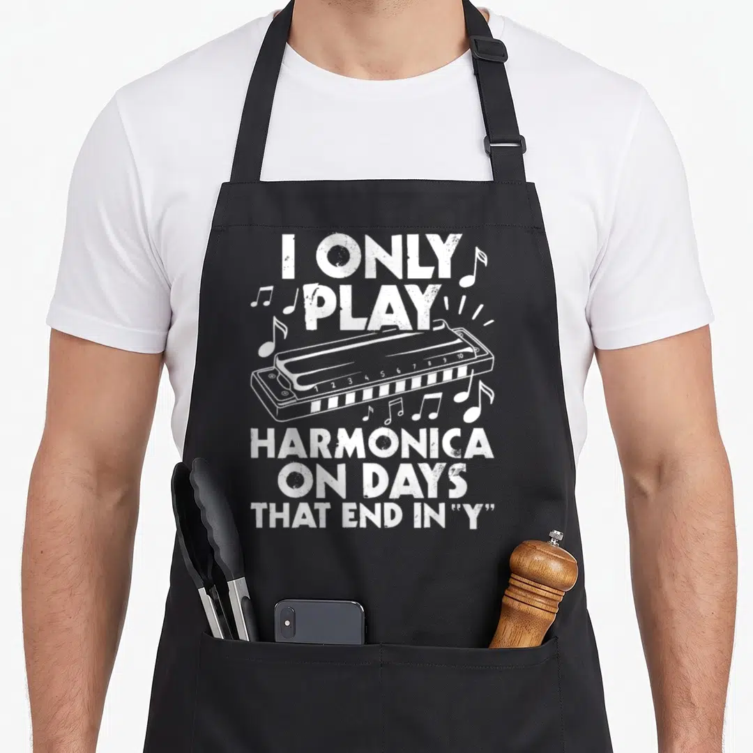 Play harmonica apron - White distressed harmonica with musical notes and text reading I Only Play Harmonica On Days — shown on a black cotton canvas apron against a white background