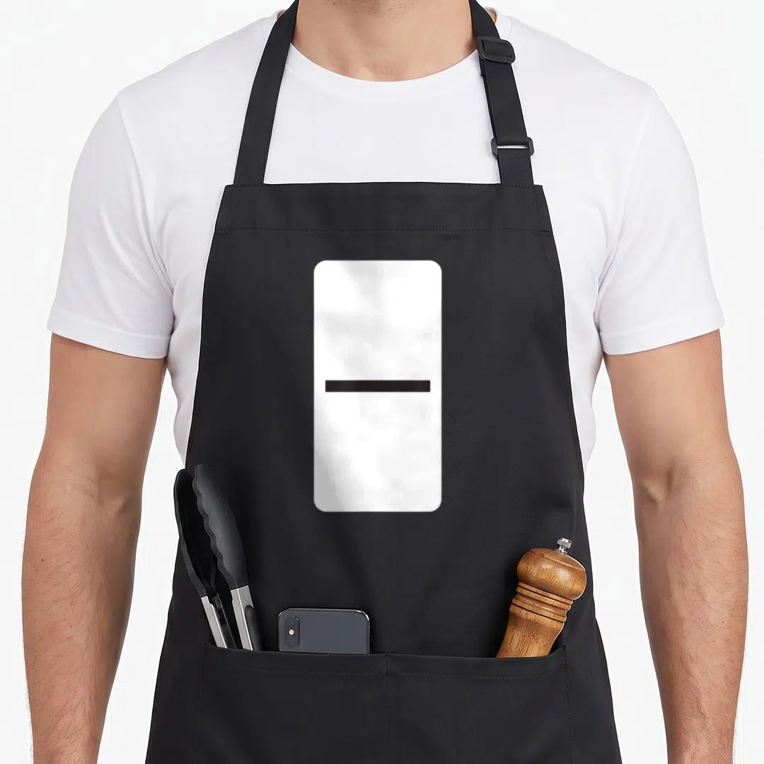 Double blank apron - White domino tile with a single centered black horizontal line — shown on a black cotton canvas apron against a white background